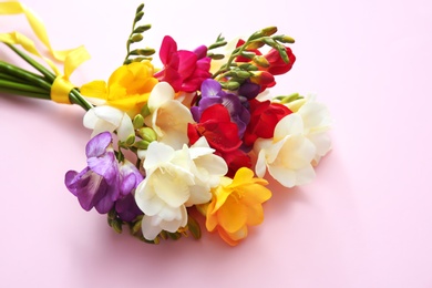 Beautiful freesia bouquet with ribbon on color background Photo of Beautiful freesia bouquet with ribbon on color background