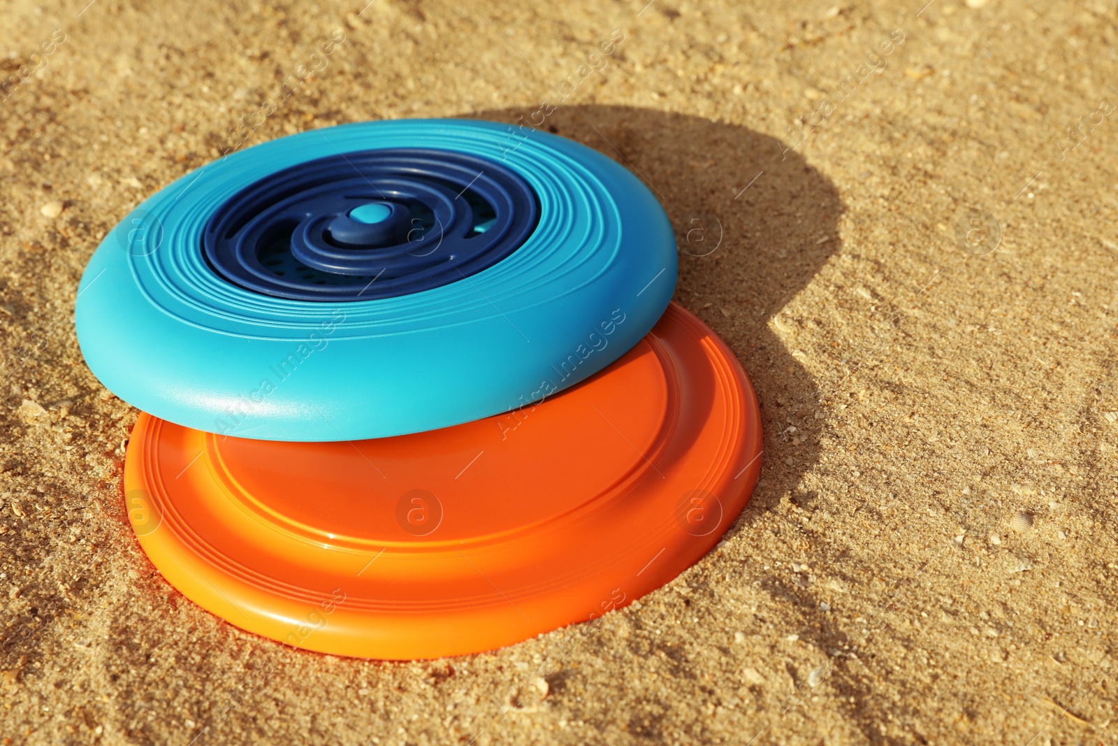 New plastic frisbee discs on sandy beach Photo of New plastic frisbee discs on sandy beach