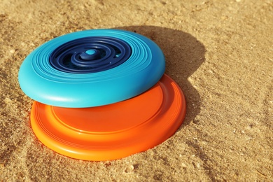 New plastic frisbee discs on sandy beach Photo of New plastic frisbee discs on sandy beach