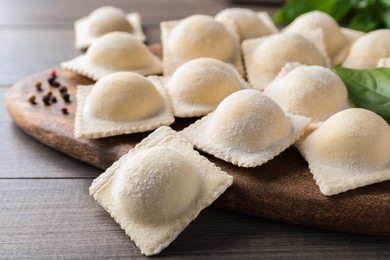 Uncooked ravioli, basil and peppercorns on wooden table, closeup Photo of Uncooked ravioli, basil and peppercorns on wooden table, closeup