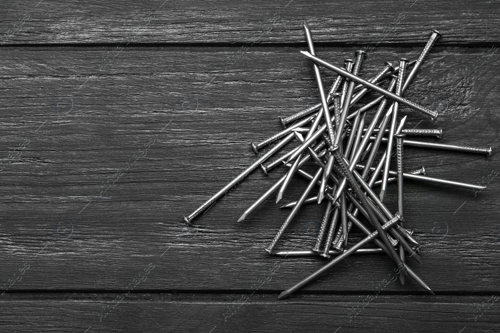Pile of metal nails on grey wooden background, flat lay. Space for text Photo of Pile of metal nails on grey wooden background, flat lay. Space for text