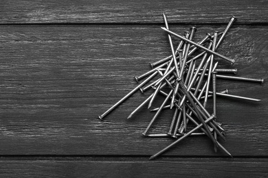 Pile of metal nails on grey wooden background, flat lay. Space for text Photo of Pile of metal nails on grey wooden background, flat lay. Space for text