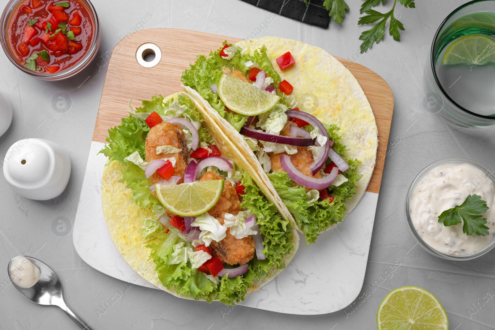 Delicious fish tacos served on light grey table, flat lay Photo of Delicious fish tacos served on light grey table, flat lay