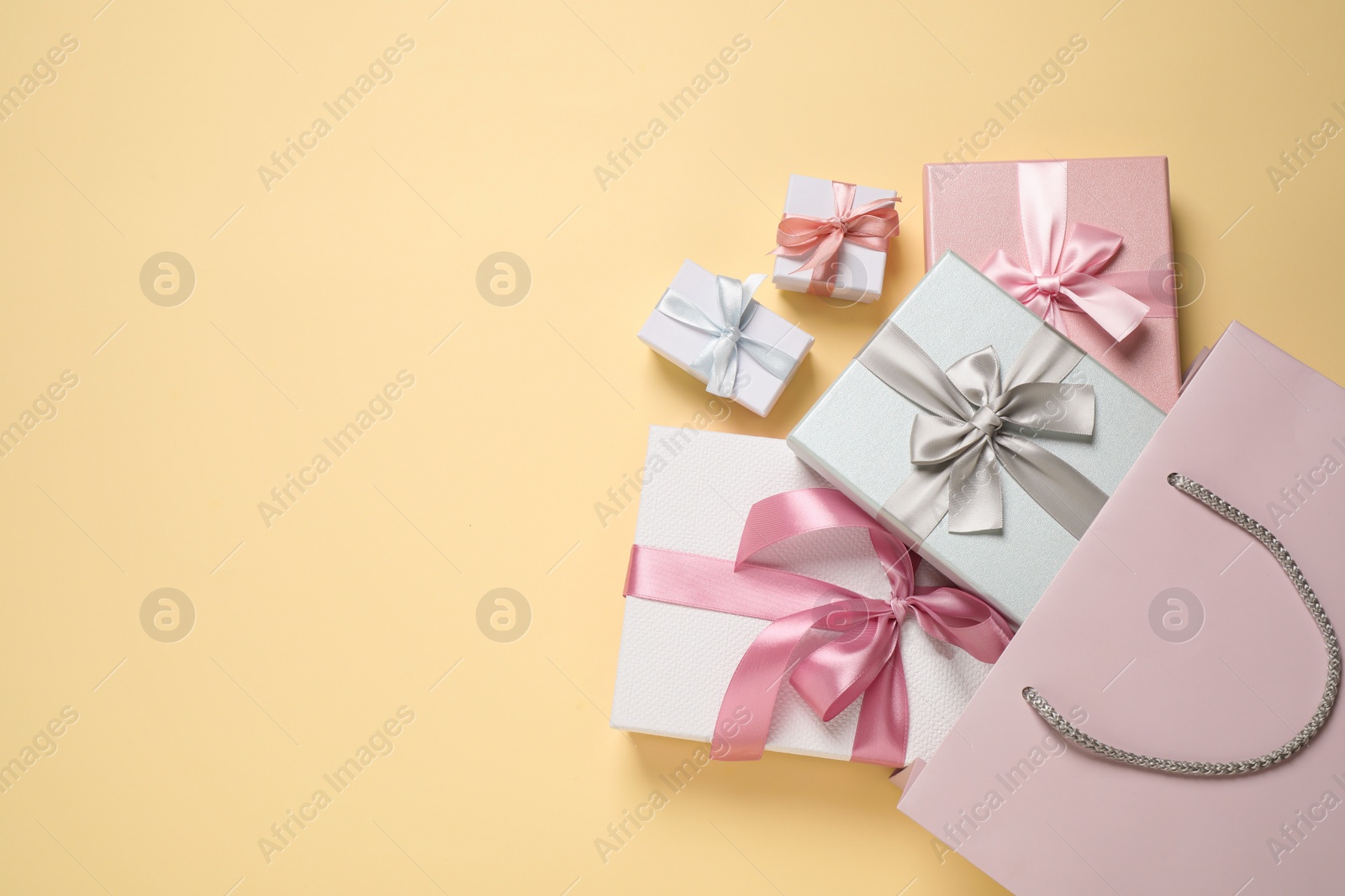 Photo of Paper bag with beautiful gift boxes on beige background, flat lay. Space for text