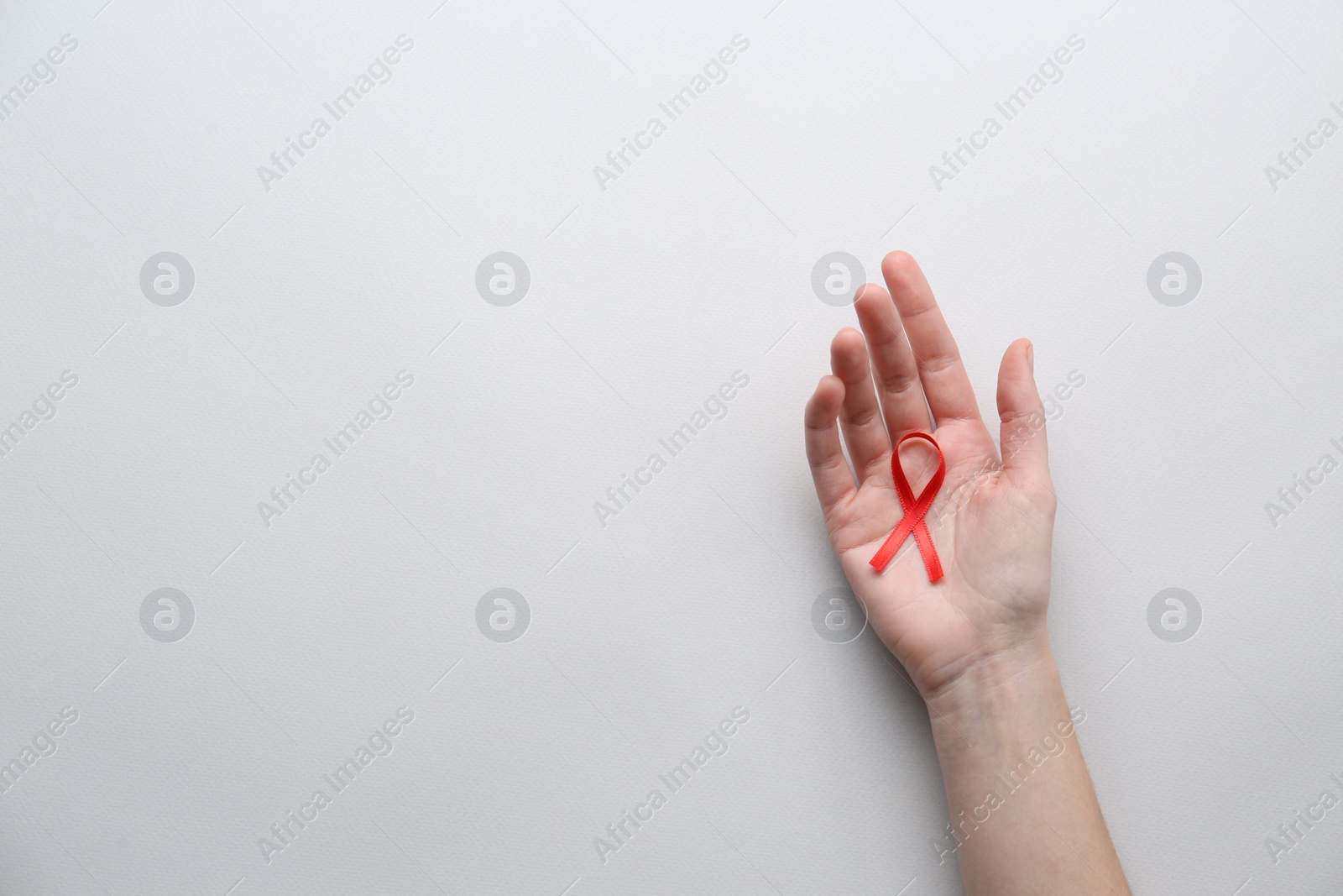 Woman holding red awareness ribbon on white background, top view with space for text. World AIDS disease day Photo of Woman holding red awareness ribbon on white background, top view with space for text. World AIDS disease day