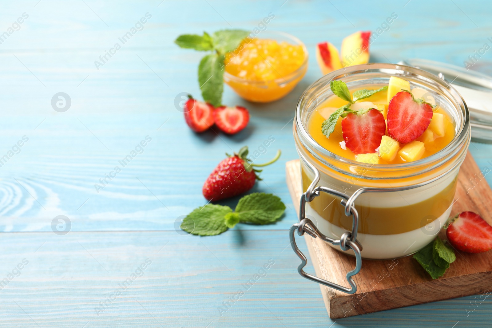 Delicious panna cotta with mango coulis and fresh fruits on light blue wooden table. Space for text Photo of Delicious panna cotta with mango coulis and fresh fruits on light blue wooden table. Space for text