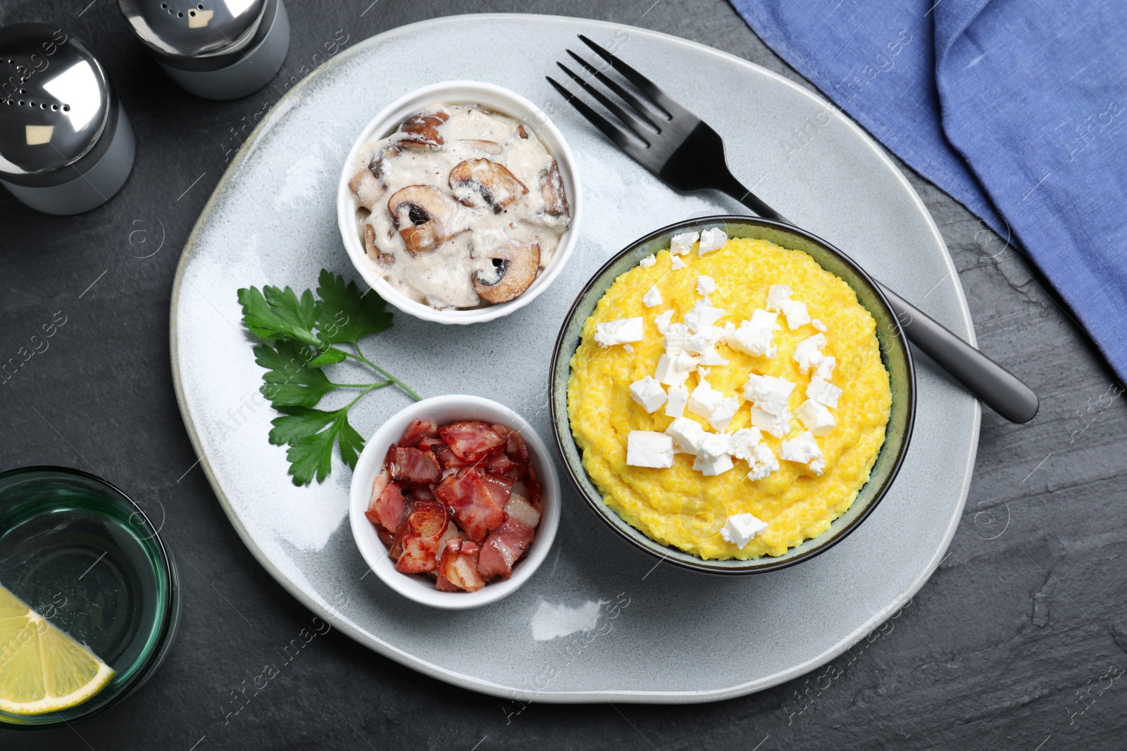 Tasty banosh served with brynza, pork cracklings and mushrooms on black table, flat lay. Traditional Ukrainian dish Photo of Tasty banosh served with brynza, pork cracklings and mushrooms on black table, flat lay. Traditional Ukrainian dish