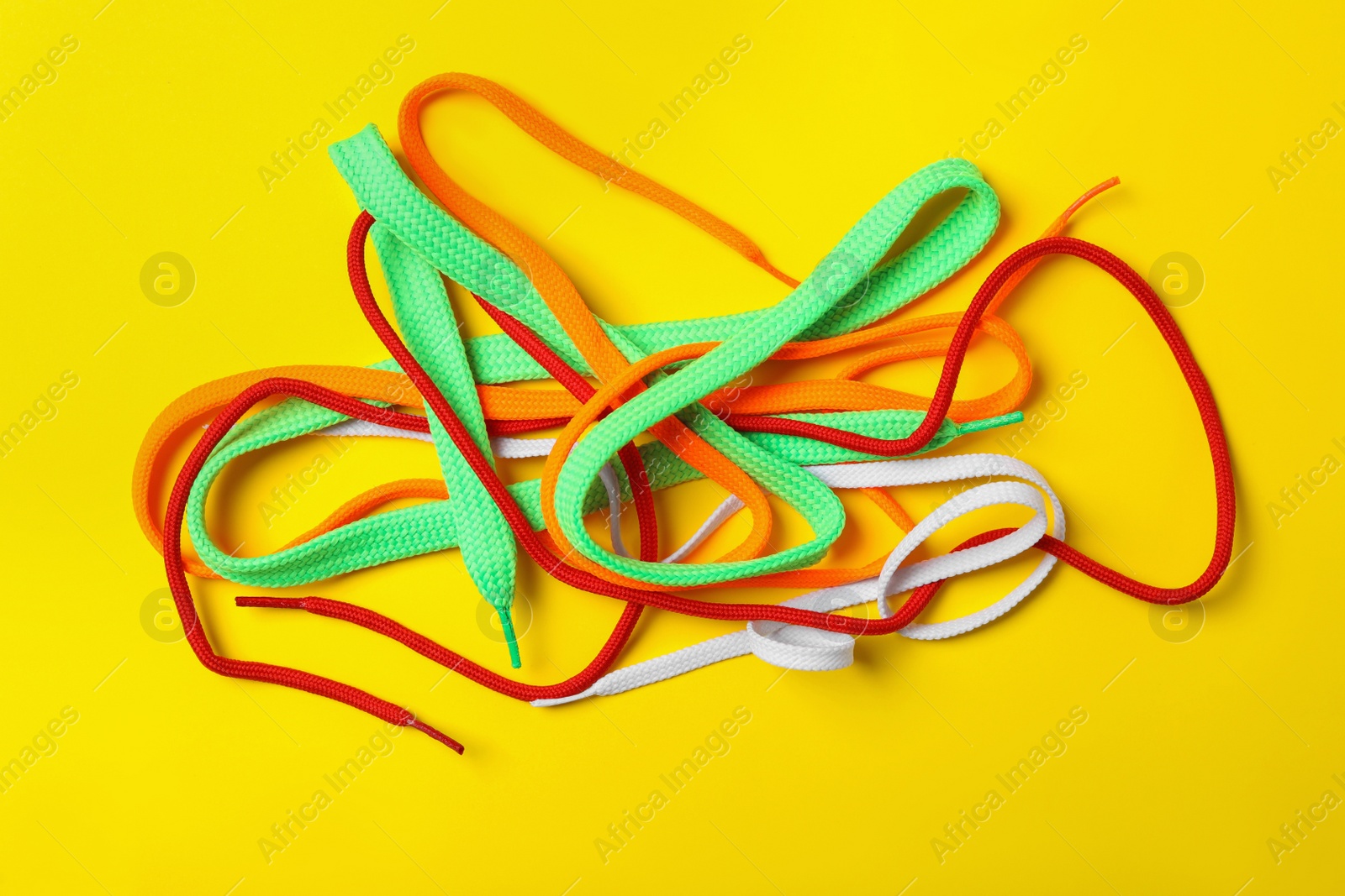 Colorful shoelaces on yellow background, flat lay Photo of Colorful shoelaces on yellow background, flat lay
