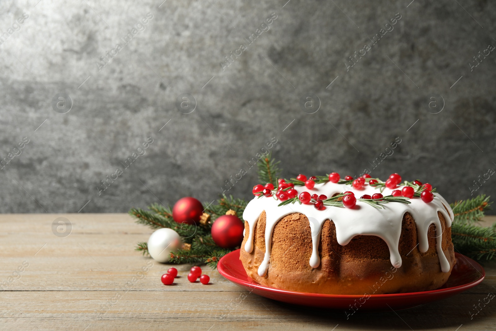 Traditional Christmas cake decorated with glaze, pomegranate seeds, cranberries and rosemary on wooden table, space for text Photo of Traditional Christmas cake decorated with glaze, pomegranate seeds, cranberries and rosemary on wooden table, space for text