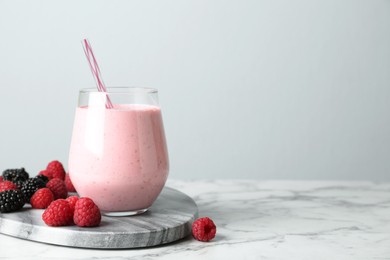 Yummy berry smoothie in glass on white marble table, space for text Image of Yummy berry smoothie in glass on white marble table, space for text