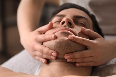 Photo of Man receiving facial massage in beauty salon, closeup