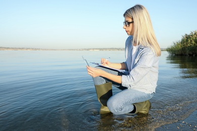Scientist with clipboard and sample taken from river Photo of Scientist with clipboard and sample taken from river
