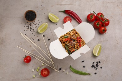 Box of wok noodles with vegetables and meat on light table, flat lay Photo of Box of wok noodles with vegetables and meat on light table, flat lay