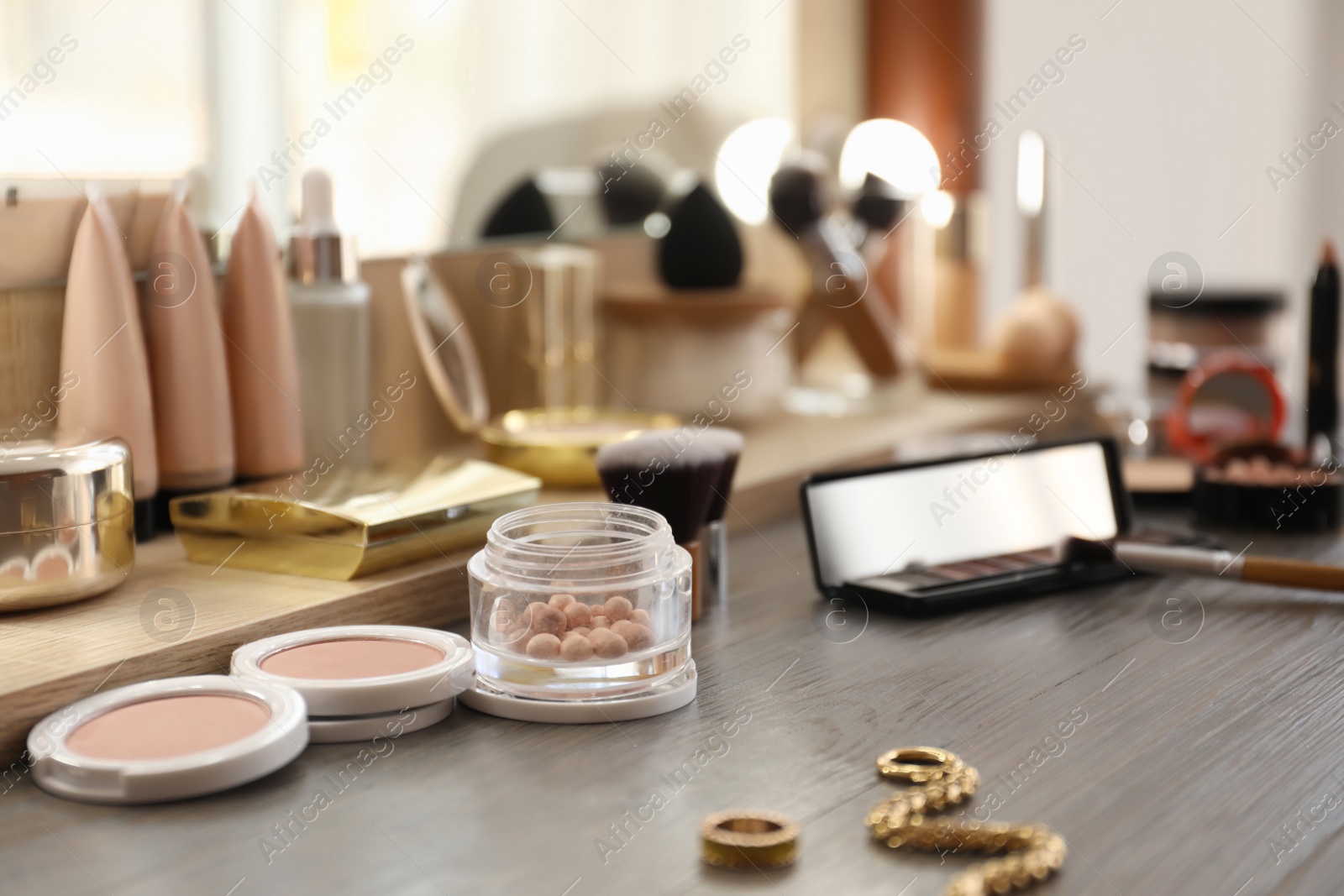 Many different cosmetic products on dressing table indoors Photo of Many different cosmetic products on dressing table indoors