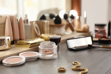 Many different cosmetic products on dressing table indoors Photo of Many different cosmetic products on dressing table indoors