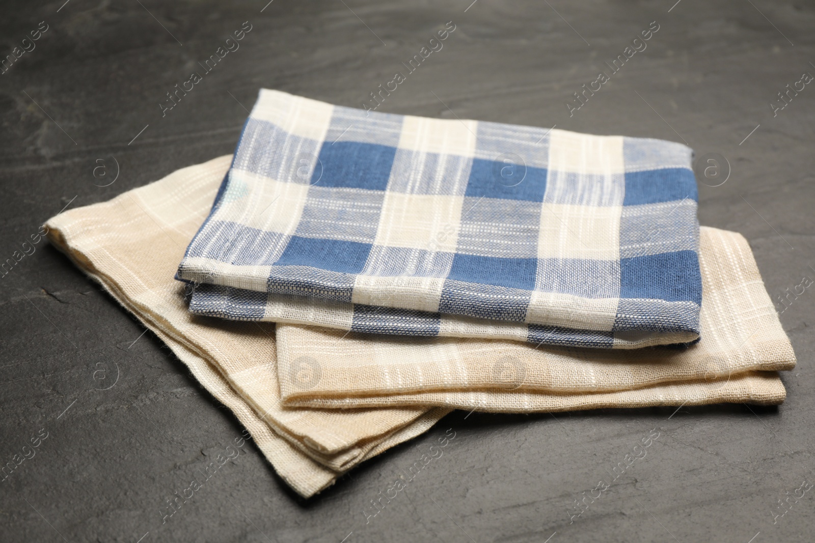 Beige and blue checkered kitchen towels on black table Photo of Beige and blue checkered kitchen towels on black table
