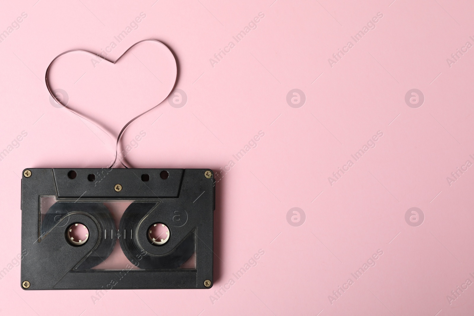 Top view of music cassette and heart made with tape on pink background, space for text. Listening love song Photo of Top view of music cassette and heart made with tape on pink background, space for text. Listening love song