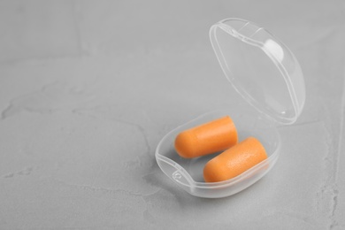 Pair of orange ear plugs in case on grey background. Space for text Photo of Pair of orange ear plugs in case on grey background. Space for text