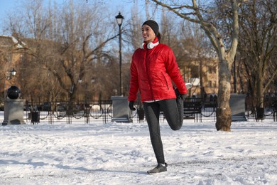 Happy woman doing sports exercises in snowy park on winter day Photo of Happy woman doing sports exercises in snowy park on winter day