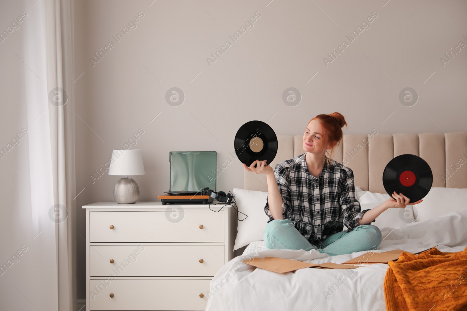 Young woman choosing vinyl disc to play music with turntable in bedroom Photo of Young woman choosing vinyl disc to play music with turntable in bedroom