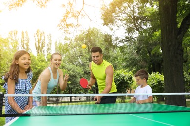 Happy family playing ping pong in park Photo of Happy family playing ping pong in park