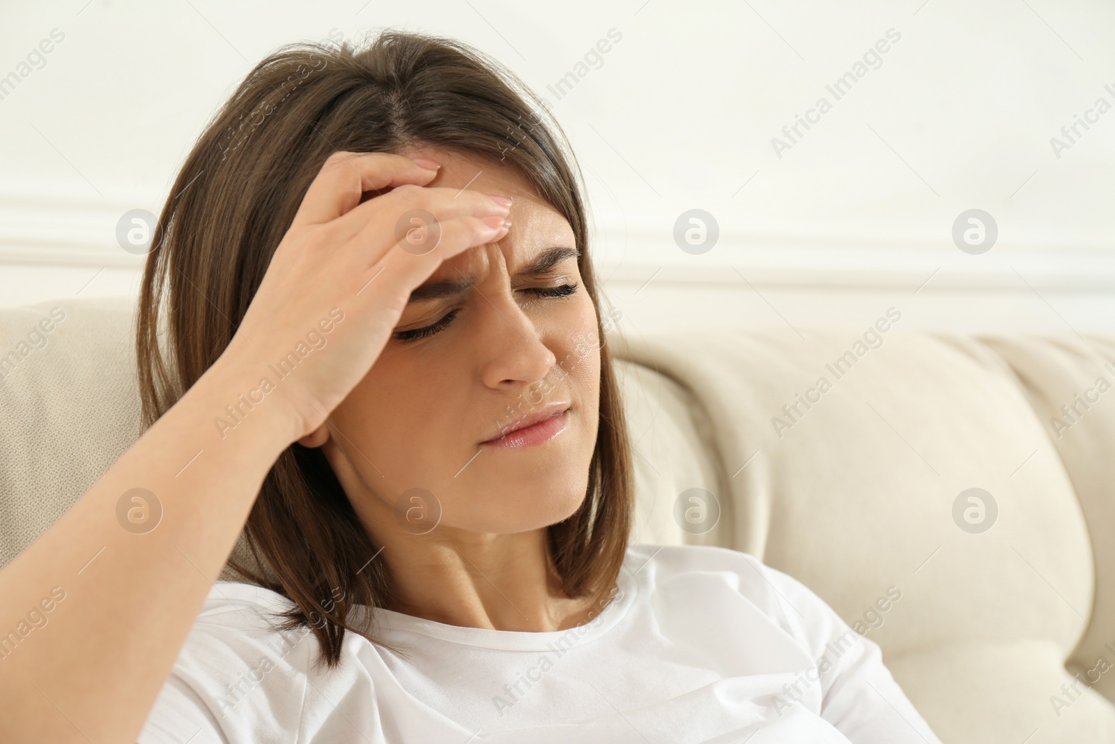 Young woman suffering from migraine on sofa at home Photo of Young woman suffering from migraine on sofa at home