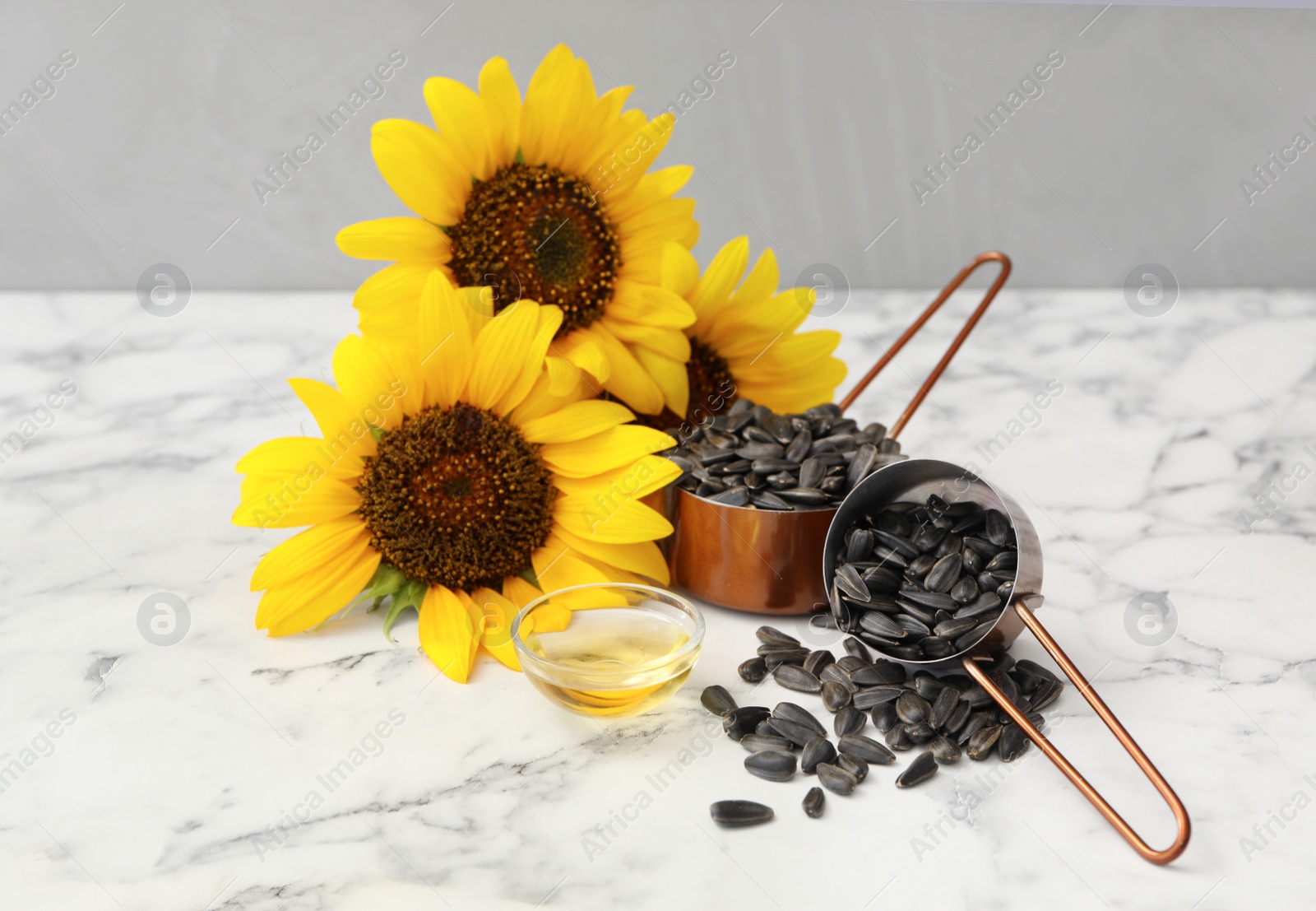 Sunflowers, oil and seeds on white marble table Photo of Sunflowers, oil and seeds on white marble table