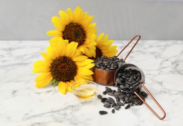 Sunflowers, oil and seeds on white marble table Photo of Sunflowers, oil and seeds on white marble table