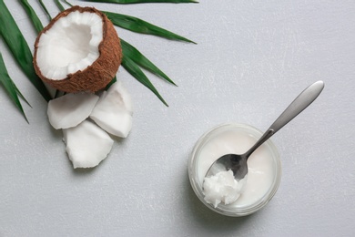 Jar with coconut oil and nut pieces on grey background Photo of Jar with coconut oil and nut pieces on grey background