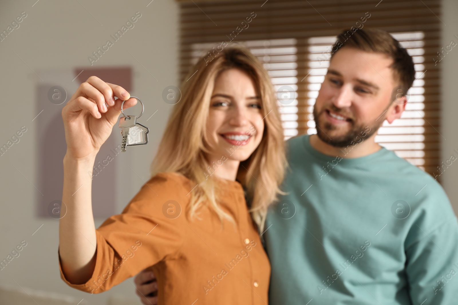 Happy young couple with key in new house, focus on hand Photo of Happy young couple with key in new house, focus on hand