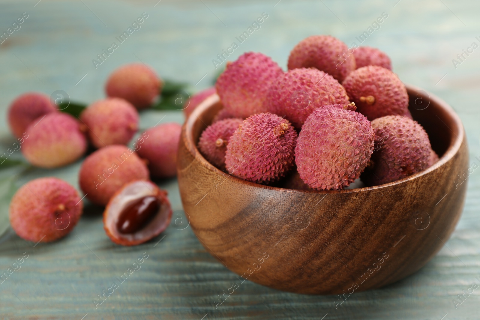 Fresh ripe lychee fruits in bowl on wooden table. Space for text Photo of Fresh ripe lychee fruits in bowl on wooden table. Space for text