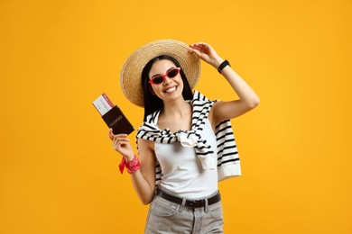 Happy female tourist with ticket and passport on yellow background Photo of Happy female tourist with ticket and passport on yellow background