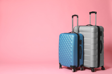 Stylish grey and blue suitcases on pink background. Space for text Photo of Stylish grey and blue suitcases on pink background. Space for text