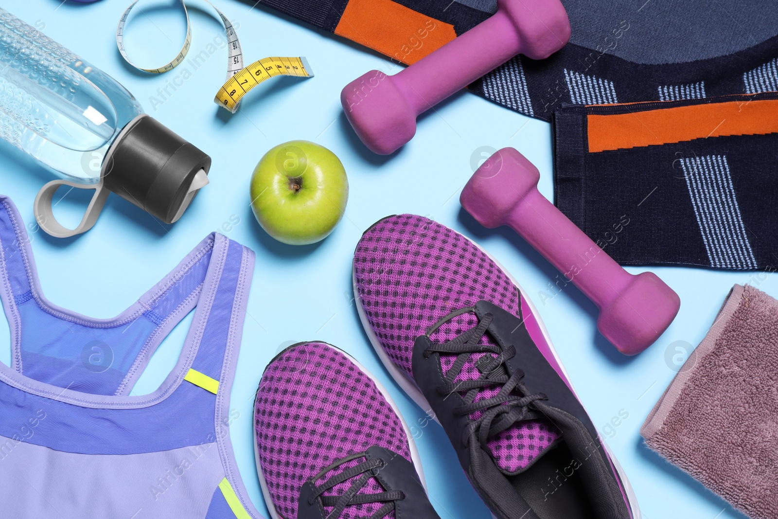 Flat lay composition with sportswear, sneakers and dumbbells on light blue background Photo of Flat lay composition with sportswear, sneakers and dumbbells on light blue background
