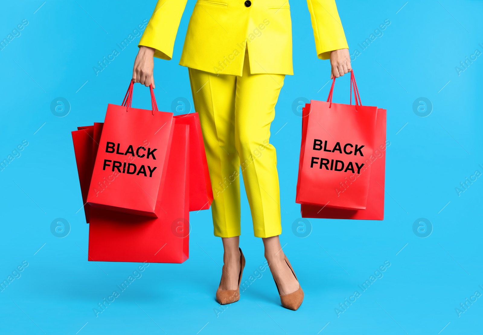 Woman with shopping bags on light blue background, closeup. Black Friday Photo of Woman with shopping bags on light blue background, closeup. Black Friday