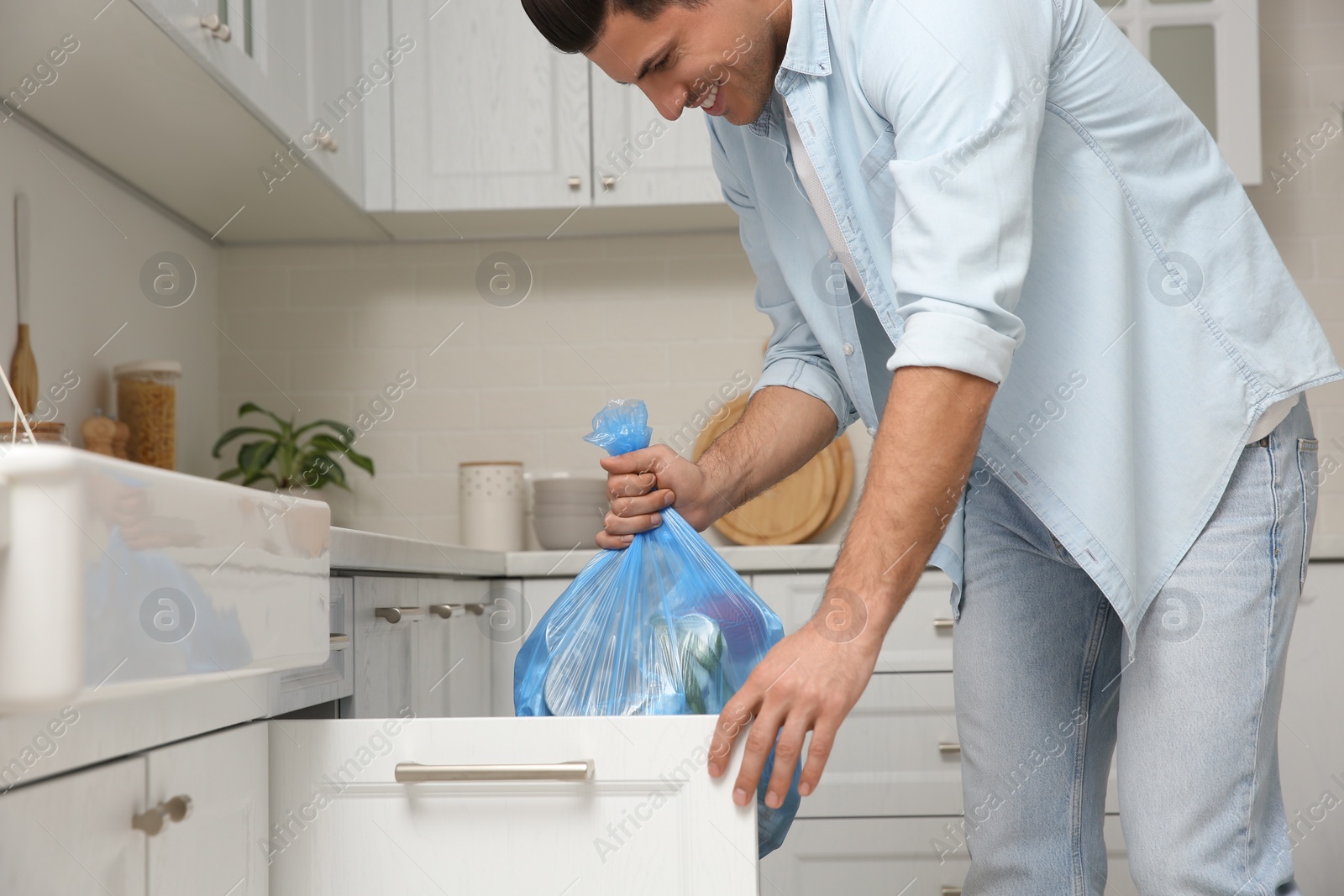 Man holding full garbage bag at home Photo of Man holding full garbage bag at home