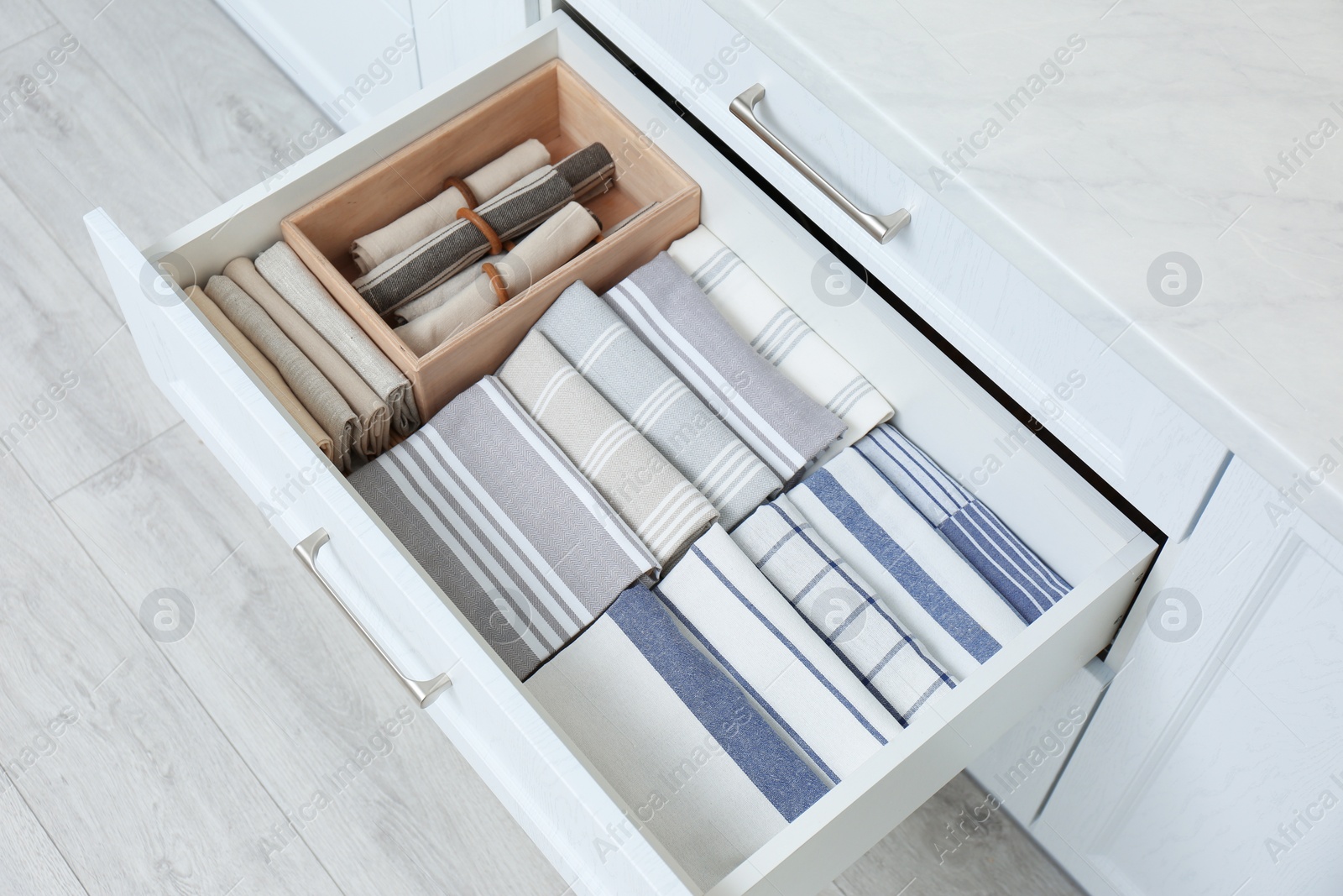 Open drawer with folded napkins and towels indoors. Order in kitchen Photo of Open drawer with folded napkins and towels indoors. Order in kitchen