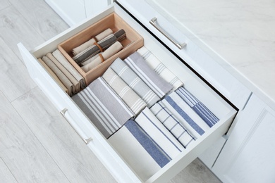 Open drawer with folded napkins and towels indoors. Order in kitchen Photo of Open drawer with folded napkins and towels indoors. Order in kitchen
