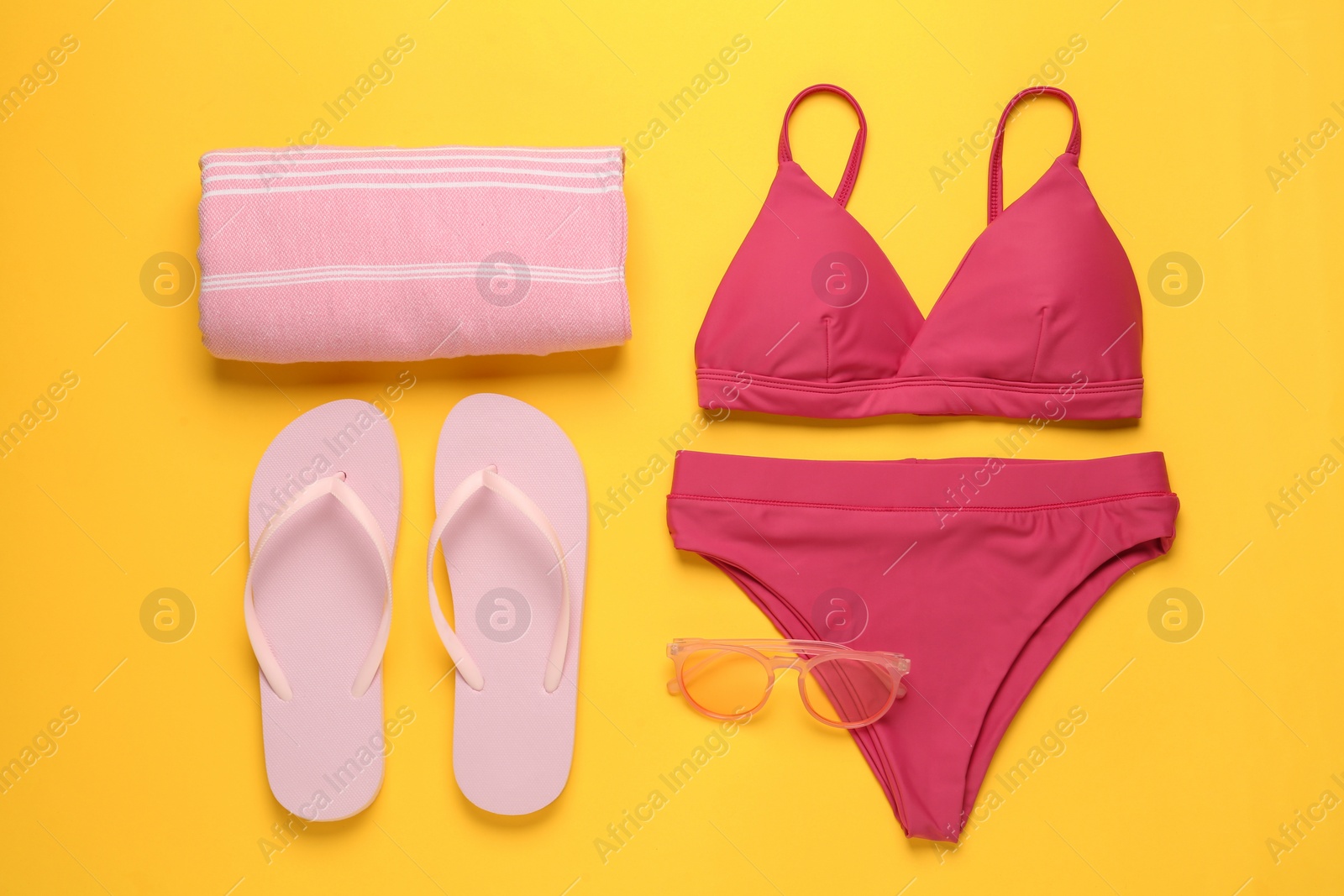 Photo of Stylish bikini and beach accessories on yellow background, flat lay
