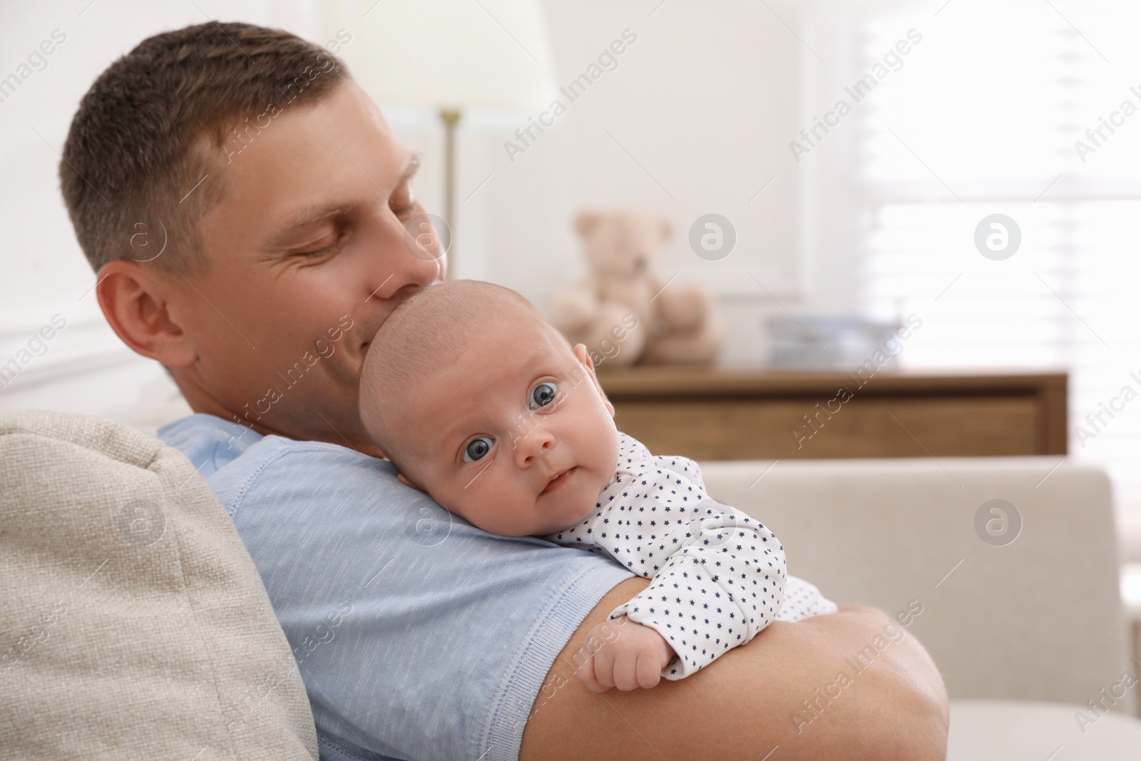 Happy father holding his cute little baby at home, space for text Photo of Happy father holding his cute little baby at home, space for text