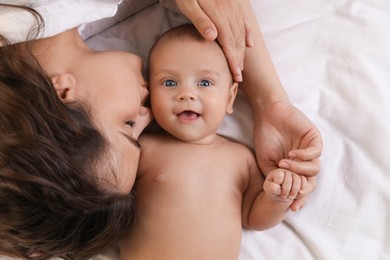Young mother with her cute baby on bed, top view Photo of Young mother with her cute baby on bed, top view