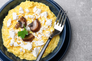 Tasty banosh served with brynza and mushrooms in bowl on grey table, top view. Traditional Ukrainian dish Photo of Tasty banosh served with brynza and mushrooms in bowl on grey table, top view. Traditional Ukrainian dish
