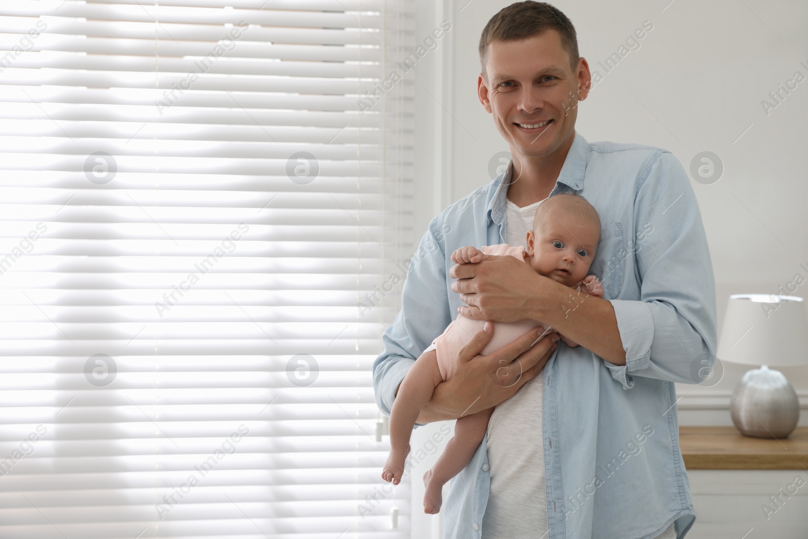 Happy father holding his cute little baby at home, space for text Photo of Happy father holding his cute little baby at home, space for text
