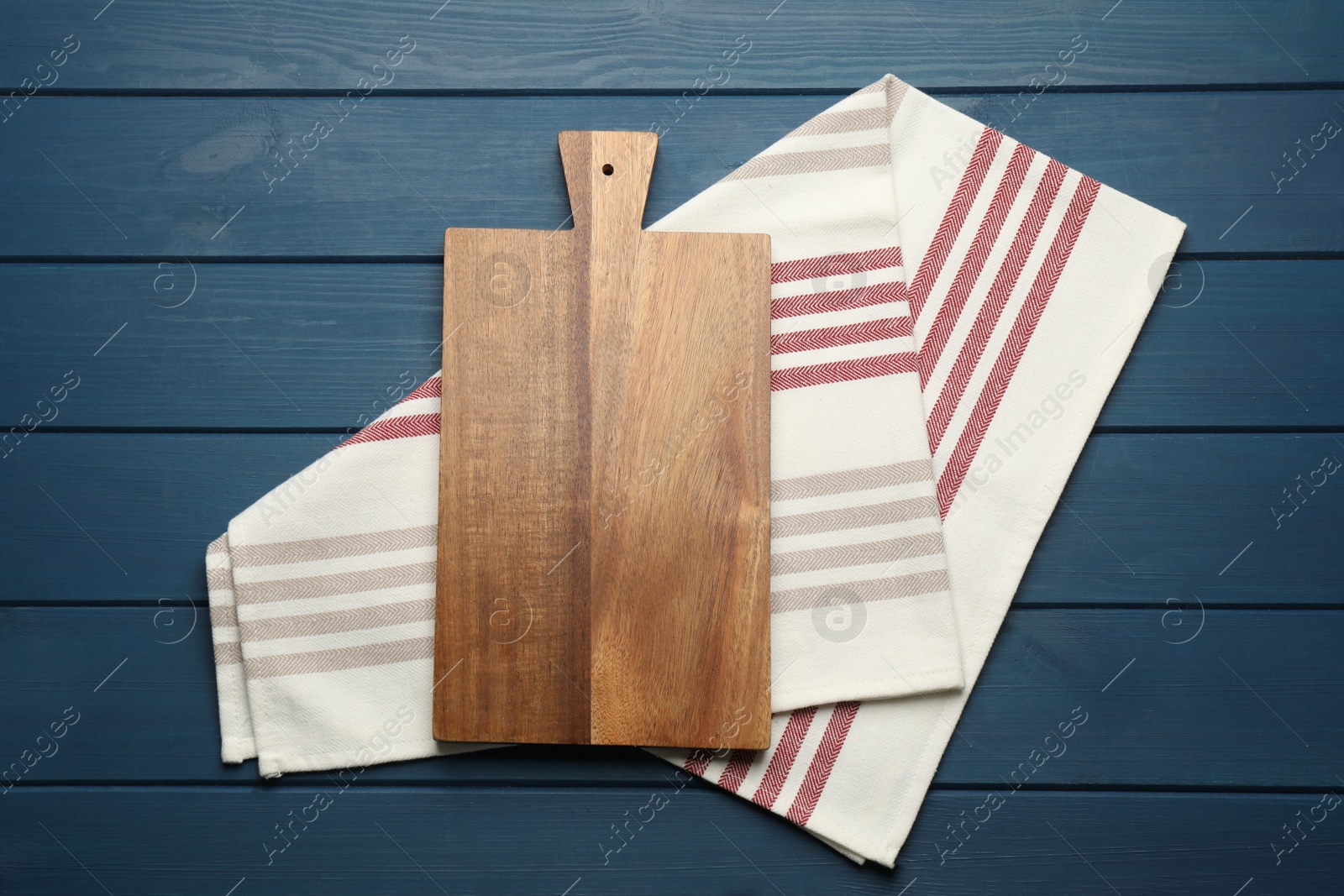 Striped kitchen towel and cutting board on blue wooden table, top view Photo of Striped kitchen towel and cutting board on blue wooden table, top view