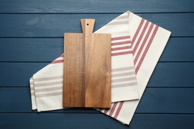 Striped kitchen towel and cutting board on blue wooden table, top view Photo of Striped kitchen towel and cutting board on blue wooden table, top view