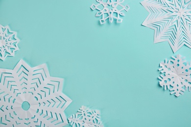 Flat lay composition with paper snowflakes on cyan background. Space for text Photo of Flat lay composition with paper snowflakes on cyan background. Space for text
