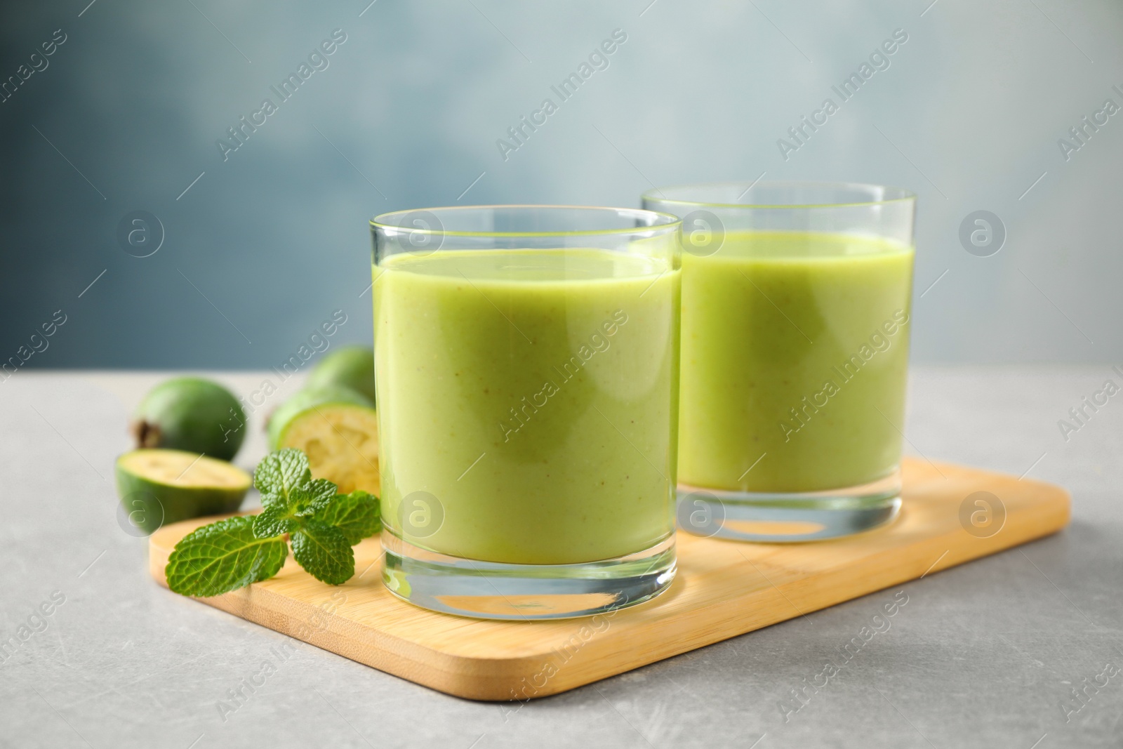 Fresh feijoa smoothie and fresh mint on grey table, closeup Photo of Fresh feijoa smoothie and fresh mint on grey table, closeup