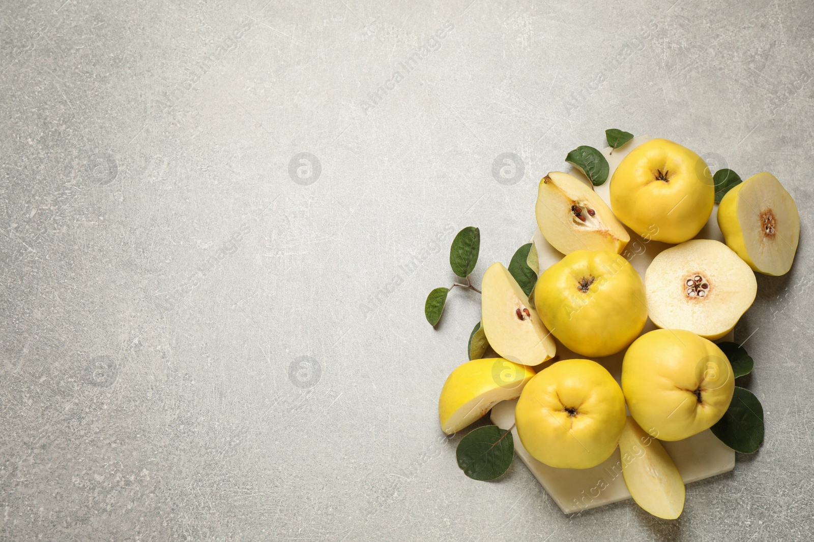 Fresh ripe organic quinces with leaves on grey table, flat lay. Space for text Photo of Fresh ripe organic quinces with leaves on grey table, flat lay. Space for text