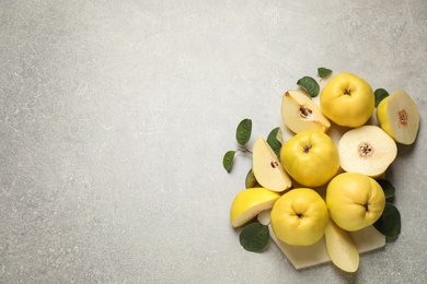 Photo of Fresh ripe organic quinces with leaves on grey table, flat lay. Space for text