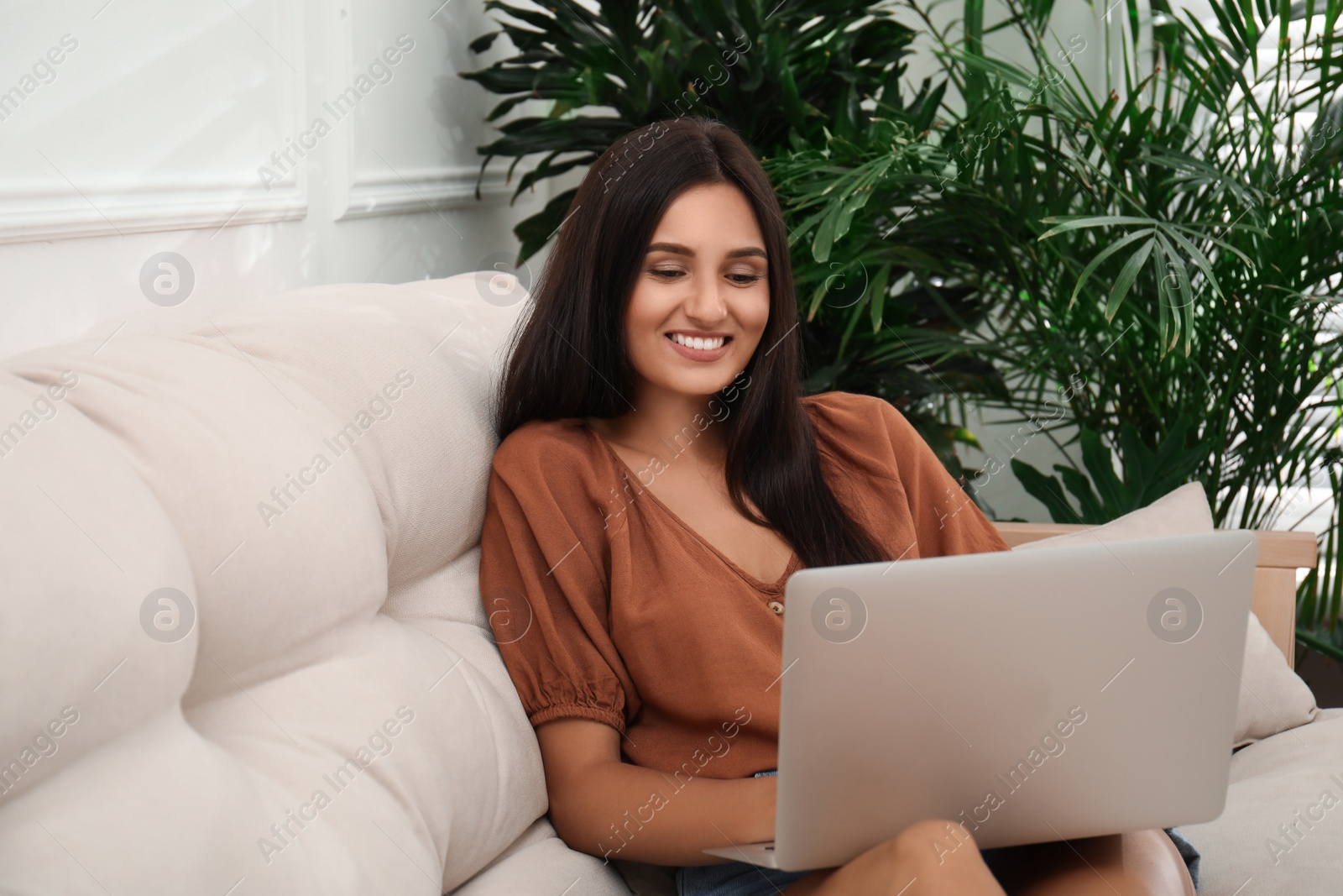 Beautiful woman using laptop on sofa in living room. Interior design Photo of Beautiful woman using laptop on sofa in living room. Interior design